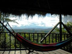 a hammock on a porch with mountains in the backgroung and trees