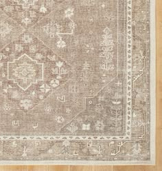 a beige rug with an ornate design on the top and bottom, sitting on a wooden floor