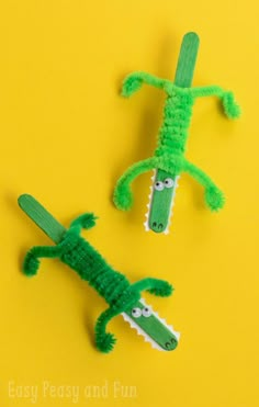 two plastic alligators are sitting next to each other on a yellow surface, one is green and the other is white