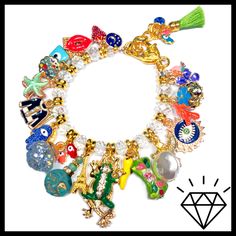 "LOADED gold charm bracelet just the way you like it with the addition of Crystals!! Tons of enamel charms with Czech crystals in between! Stunning! 7 3/4\" length with Lobster Clasp and adjustment chain. Actual charms may vary. All of my jewelry is handmade by me. No two are exactly alike. Hence the name, \"OKO by Andy\" (One-of-a-Kind). The photos in the listings are indicative of the style you will receive, not necessarily an exact representation since these are not mass made in a factory." Gold Charm Bracelet As A Souvenir, Enamel Charms Bracelet, Enamel Bracelet Jewelry With Lobster Clasp, Enamel Bracelet With Lobster Clasp, Gold Enamel Bracelets With Charms, Gold Enamel Bracelet With Charms, White Dangle Charm Bracelet With Lobster Clasp, Gold Enamel Charms With Removable Details, Gold Charm Bracelet