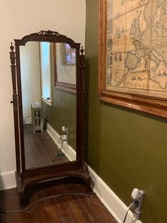 a mirror sitting on top of a hard wood floor next to a wall with a map