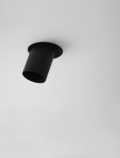 a black light fixture hanging from the ceiling in a room with white walls and flooring