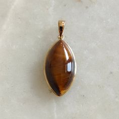 ITEM DESCRIPTION: >> The pendant is made from Solid 14K Yellow Gold. Gemstone used is absolutely natural and ethically sourced.  >> Natural Tiger Eye in Cabochon Marquise shape with bezel setting is studded on it with utmost precision.  >> This is a minimalist design and is absolutely hassle-free and everyday jewelry.  Gem: Tiger Eye Gem size: 11x21 mm  Gem weight: 11.57 carats Gold purity: 14K (58.33% approx.) Gold weight: 0.57 grams  Gross weight: 2.88 grams The Gold purity is guaranteed and it comes with authentic 14K gold hallmark. Since these Pendants are handmade, they are Nickel/Lead FREE.  CUSTOMISATION: --> Gemstone customization is available and the main gemstone can be substituted with a gem of your choice. --> You can choose your own gemstone --> Kindly drop a message for more Gold Teardrop Gemstones Fine Jewelry, Polished 14k Gold Amber Jewelry, 14k Gold Amber Jewelry With Polished Finish, Gold Teardrop Gemstones For Formal Occasions, Gold Teardrop Gemstones For Formal Events, Elegant Gold Oval Pendant Gemstones, Formal Gold Teardrop Gemstones, Fine Jewelry Cabochon Gemstones For Gifts, Fine Jewelry Cabochon Gemstones As Gift