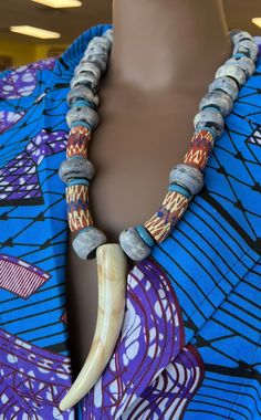 This Tribal necklace makes with indigo imported beads from Gambia. A true stand out and amazing. Piece . This precious necklace is s4 inches in length.  long. This necklace would look great on solid color garments.The color of the handmade jewelry make you calm and reminds of the calm sounds of the ocean. The horn pendant is a replica horn. Don't delay order yours today, Traditional Blue Wooden Beads, Unique Wooden Beads Necklace For Festivals, Unique Wooden Beaded Necklaces For Festivals, Unique Beaded Necklaces With Wooden Beads For Festivals, Artisan Fair Trade Beaded Necklace For Festivals, Artisan Necklaces With Wooden Beads For Rituals, Artisan Necklace With Wooden Beads For Rituals, Artisan Wooden Beads For Festivals, Bohemian Wooden Beads For Rituals