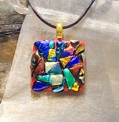 A unique, kiln fused, dichroic glass pendant, custom designed for you, arranged capped with a patchwork of bold,bright and shiny multi-colored textured shapes on a red base and has a black leather cord necklace & 1.5 inch extension chain and nickel-free, silver-plated clasp.  A fashionable accessory & stylish as a chic & modern, sparkling glass necklace.  Dress up blue jeans, relax in loungewear or accent your evening attire.  Created & handcrafted in a home workshop. Select an original mosaic art glass pendant to add to your jewelry collection or as a gift for a loved one, friend, nurse, teacher, etc. An organza gift bag is included with your order. Thanks for visiting. Aloha! designworksbyfaye.etsy.com www.etsy.com/shop/DesignWorksByFaye Multicolor Recycled Glass Beads For Jewelry Making, Multicolor Recycled Glass Jewelry For Jewelry Making, Hand Painted Czech Glass Jewelry For Gift, Hand Painted Czech Glass Jewelry Gift, Hand-painted Czech Glass Jewelry Gift, Multicolor Recycled Glass Jewelry As A Gift, Multicolor Recycled Glass Jewelry For Gifts, Handmade Multicolor Recycled Glass Jewelry, Handmade Round Necklace With Eco-friendly Glass