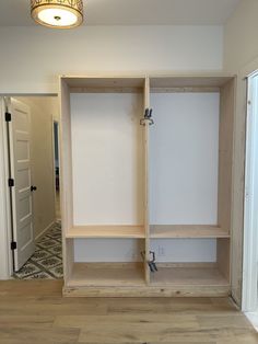 an empty room with white walls and wooden shelves on the wall, in front of a doorway