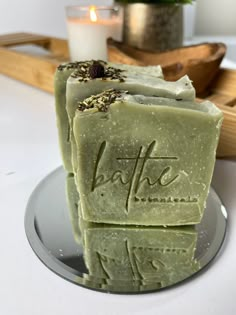 two bars of soap sitting on top of a plate next to a candle and tray