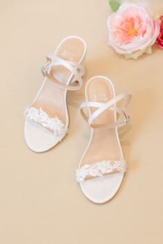 a pair of white shoes sitting on top of a table next to a bouquet of flowers