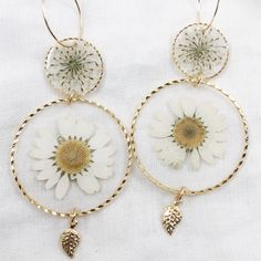 24k gold plated round dangle statement earrings made with real pressed flowers set in crystal clear resin. The small circle contains queen anne's lace, and the large circle contains a daisy. Perfect for nature lovers! These preserved botanical earrings are super lightweight and will make a statement! Pendants/charms: 24k gold plated brass Earring hoops: gold plated brass Follow us on Instagram at instagram.com/grabbagbotany to see our latest collection drops on our website, grabbagbotany.com. Th Delicate Birth Flower Earrings For Anniversary, Yellow Gold Flower Earrings, Gold Plated Flower Earrings For Weddings, Gold Plated Round Flower Earrings For Wedding, Gold Birth Flower Earrings For Anniversary, Gold Earrings With Birth Flower For Anniversary, Elegant Pressed Flower Drop Earrings, Botanical Jewelry With Pressed Flowers, White Flower-shaped Gold Plated Jewelry