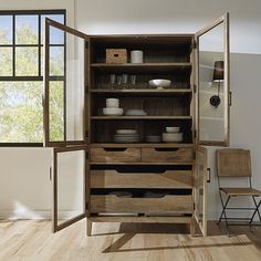 an open wooden cabinet with dishes on it