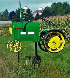 a green and yellow tractor sitting on top of a grass field next to a pole