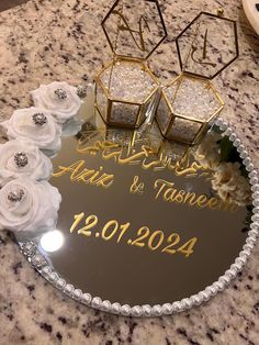 the wedding cake is decorated with white flowers and gold lettering on it's glass plate