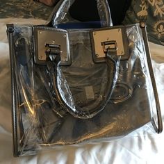 This satchel and tote handbag is 2-in-1. It's a transparent satchel tote with a complimentary removable shoulder bag. This bag is awesome! If you love chic bags, this is the perfect bag for you!

2-day processing. Shipped in 4-7 days. Trendy Bags With Clear Strap And Top Handle, Trendy Top Handle Shoulder Bag With Clear Strap, Trendy Top Handle Bag With Clear Strap, Clear Crossbody Bags For Shopping, Daily Use Top Handle Shoulder Bag With Clear Strap, Clear Strap Shoulder Bag Satchel For Shopping, Modern Satchel Bag With Clear Strap, Clear Top Handle Shoulder Bag For Everyday Use, Chic Shoulder Bag With Clear Strap For Travel