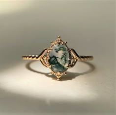 a close up of a ring with a stone in it on a white table top