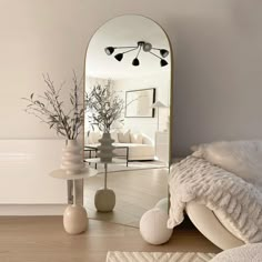 a mirror sitting on top of a wooden floor next to a vase filled with flowers