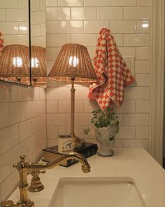 a bathroom sink with two lamps on top of it