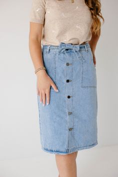 Create an instant feminine look wearing the 'Cassidy' Skirt! Featuring a button-front design and tie waist, this denim midi skirt makes a perfect choice for both casual or formal occasions. The soft, lightweight denim in a regular fit offers comfort, while the pull-on style allows easy wear. Pair the 'Cassidy' with a black tee and sneakers for a fun day in the city or running errands in town! 75% Cotton 25% Polyester Hand Wash Cold Do Not Bleach Hang to Dry Low Iron if Needed Model Height 5'7" | Spring Workwear Skirt With Buttoned Pockets, Casual Midi Length Denim Skirt With Pockets, Casual Midi Denim Skirt With Pockets, Casual Midi Bottoms With Button Closure For Day Out, Chic High Waist Denim Skirt With Button Closure, Chic Skirt With Buttoned Pockets For Spring, Spring Midi Denim Skirt, Midi Length Bottoms With Button Closure For Day Out, Casual Midi Skirt With Button Closure For Day Out