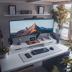 a computer monitor sitting on top of a desk next to a keyboard, mouse and plant