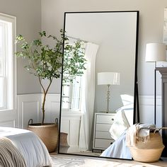 a large mirror sitting on top of a bed next to a plant in a vase