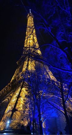 the eiffel tower lit up at night with blue lights in paris, france