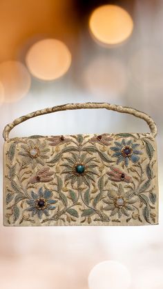 This stunning 1950s gold satin clutch/bag has been intricately hand embroidered in the zardozi style with shimmery gold metallic threads, embellished with genuine semi-precious stones, creating an opulent and sophisticated effect.  The front of this clutch features the amazing hand embroidered design, and the back is solid satin with an attached hand strap with embroidered detail. There is an attached gold satin cord crossbody strap which can easily be tucked inside if you like. The interior is Formal Clutch, Satin Clutch, Gold Satin, Hand Strap, Metallic Thread, Vintage Pieces, Precious Gemstones, Embroidered Design, Clutch Handbag