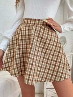 a woman in a white shirt and brown plaid skirt is posing for the camera with her hands on her hips