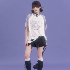 a woman in short shorts and boots standing on a purple background with her legs crossed