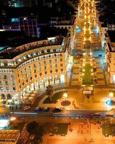 an aerial view of a city at night with lights on the buildings and cars driving down the street