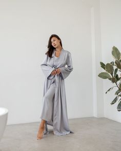 An elegant robe made of Armani silk fabric is presented in a maxi length. The model is styled with long wide sleeves and a belt. The robe emphasizes the figure well and goes well with a nightgown. Available in the following sizes: 42-46 and 48-52 Sizes: This PJ is available in sizes S-M, L-XL Body Measurements: Size  S - M:  Bust measurement - 45-48 cm,   Hips - 51 сm (stretches),  Robe length - 140 cm,  Sleeve length - 53 cm Size  L - XL:  Bust measurement - 50-54 cm,   Hips - 57 сm (stretches),  Robe length - 142 cm,  Sleeve length - 53 cm Colors: Black, White, Gray Materials:  All PJ sets are made of comfortable Armani silk. It's a breathable and allergy-friendly material. Great in terms of thermoregulation.  Fabric content:  Armani silk (50% silk, 45% viscose, 5% elastane) Breathable W Long Silk Robe For Wedding Night, Elegant Long Silk Kimono, Elegant Silk Floor-length Robe, Elegant Floor-length Silk Robe, Elegant Long Sleeve Sleepwear Set, Long Silk Robe For Daywear, Silk Long Sleeve Kimono For Daywear, Silk Long Sleeve Robe For Wedding Night, Long Sleeve Silk Robe For Wedding Night