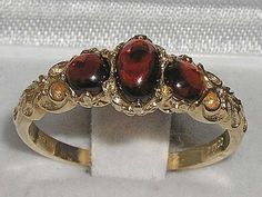 "This elegant 3 stone ring is made from solid yellow gold and set with natural cabochon cut garnets.  One centre oval cut 6x4 mm (0.24\" x 0.16\") and two round cut 4mm (0.16\") rich red garnets contrast beautifully with the yellow gold for a timeless look.  Total gem weight: 1.21ct Total Height 3mm, Width 20mm, Length 7mm The ring is completely made from solid yellow gold in your chosen karat. It will be independently tested and Hallmarked by the London or Birmingham Assay Office, so you can be Tamil Astrology, 3 Stone Ring, Trilogy Ring, Carved Ring, English Antiques, Vintage Style Rings, Red Garnet, Vintage Jewellery, Gold Gold