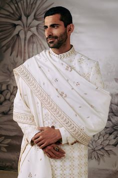 Ivory full sleeve sherwani with all over blooming flower embroidery in resham and zari work. Paired with an inner kurta and trouser. Comes along with embroidered stole.
Components: 4
Pattern: Embroidery
Type Of Work: Resham, Zari, Blooming Flower
Neckline: Stand Collar
Sleeve Type: Full Sleeves
Fabric: 100% Silk 
Color: Ivory
Other Details: 
Flower vine embroidered stole
Occasion: Groom,Wedding - Aza Fashions Cream Sherwani With Chikankari Embroidery And Long Sleeves, Cream Long Sleeve Sherwani With Chikankari Embroidery, Wedding Sherwani With Floral Embroidery In Traditional Drape, Wedding Sherwani With Floral Embroidery And Traditional Drape, Wedding Sherwani With Floral Embroidery, Traditional Sherwani With Floral Embroidery For Festivals, Traditional Off White Sherwani With Intricate Embroidery, Traditional Off-white Sherwani With Intricate Embroidery, Ceremonial White Dupatta With Naqshi Detail