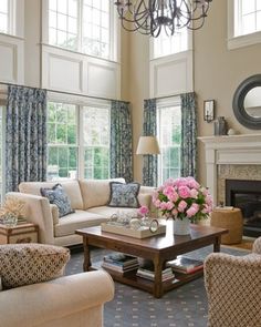 a living room filled with furniture and a chandelier hanging from the ceiling over a fire place