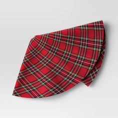 a red and green plaid tie laying on top of a white surface with a gray background