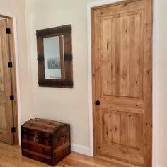 an empty room with two wooden doors and a mirror on the wall next to a trunk