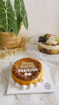 there is a birthday cake on the table next to some other cakes and plants in baskets