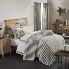 a bed room with a neatly made bed and wooden dresser next to the window in front of it