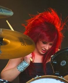 a woman with red hair playing the drums