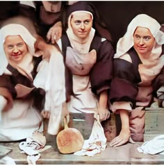 three women dressed in nun costumes posing for a photo with some bread on the counter