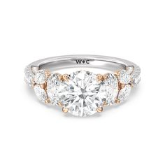 a three stone engagement ring with round diamonds on the sides and two tone gold accents