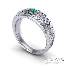 a white gold ring with an emerald stone in the center and filigrees on it