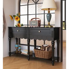 a black console table with two drawers and a lamp on top, in front of a large window