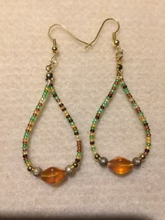 a pair of beaded earrings with glass beads and gold - toned tears