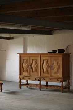 a wooden cabinet sitting in the middle of a room next to a table with two bowls on it