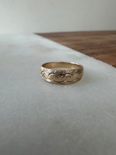 a gold wedding ring sitting on top of a wooden table