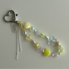 a key chain with charms attached to it on a white surface and a heart shaped charm hanging from the end