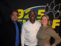 two men and a woman standing in front of a sign