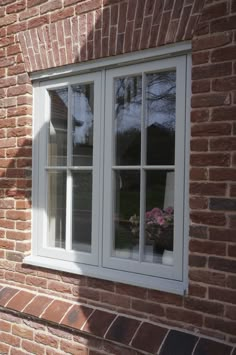 a red brick building with white windows and flowers in the window sill on the side