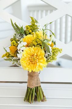 a bouquet of yellow flowers sitting on top of a white bench