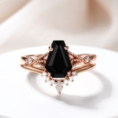 a black diamond ring sitting on top of a white plate with some diamonds around it