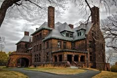 an old brick house with two chimneys on the front and one in the back, surrounded by trees